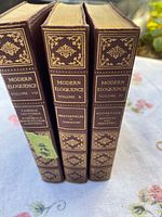 Spine view of 3 hardcover books titled Modern Eloquence volumes VIII, X, and IV, showing decorative gold embossing and volume details.