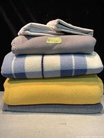 Stacked blankets and pillow cases viewed from the front, showing colors, textures, and sizes.