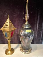 Both lamps side by side on a table against dark background, showing the antique brass candle holder and vintage floral lamp