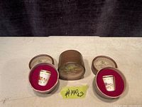 Three Royal Albert porcelain thimbles in original round boxes with red velvet interiors, lids removed to show thimbles.