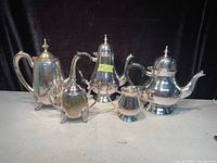 Photo of silver plated tea and coffee set including two coffee pots, a tea pot, a creamer, and a sugar bowl.