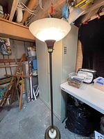 Full view of the tall floor lamp with lit frosted glass shade showing its ambient light effect and placement in a room.