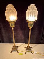 Front view of both lamps illuminated on table against dark backdrop