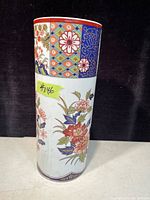 Front view of tall Imari vase decorated with detailed floral and geometric patterns in red, blue, and green.