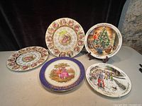 Group photo of 5 decorative plates showing different styles and sizes including Christmas and romantic scenes.