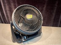 Front view of black table fan showing spiral grill and sturdy base.