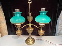 Front view showing the full lamp with emerald green glass shades and brass base.