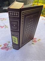 Book standing showing front cover and spine with gold gilt decorations and labels.