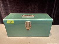 Front view of the green metal box with latch and handle visible