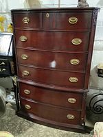 Full view of the wood tall boy dresser showing 6 drawers with brass oval handles and wood finish.