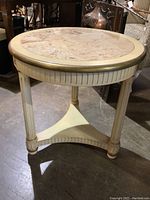 Side view of circular wooden end table with fluted legs and stone inset top.