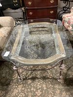 Top view of square glass coffee table showing clear beveled glass top and ornate carved frame underneath.