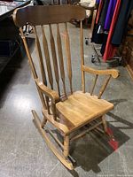 Full view of traditional wooden rocking chair showing slatted back, wooden arms, and rockers