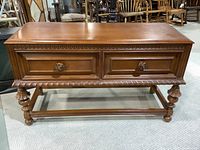 Front view of the Victorian style sideboard showing two decorated drawers and carved details under the top and on legs.