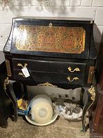 Front view of entire desk showing drop-front with brass marquetry, two lower drawers, and cabriole legs