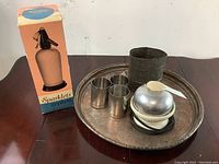Vintage kitchen lot with egg cooker, Sparklets seltzer bottle in box, tarnished silver-plated tray, three small silver-plated cups, and a metal cylindrical holder.