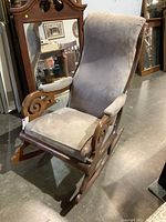 Side angle view of vintage rocking chair showing wooden scroll armrests and ultra suede cushioned seat and back.