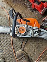 Photo of Stihl MS291C chainsaw with 18-inch bar and chain on floor near power cords.