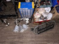 Overview of the lot showing hardware organizer, pot light housings, rolls of electrical tape, plumbing fittings, and metal bracket on floor
