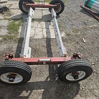 Tow dolly frame showing both axles and four wheels on paved ground