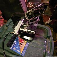 Side view of the Nikon S-ke microscope on a green plastic surface with a software disc visible in foreground