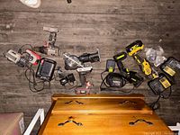 Photo showing a variety of power tools including cordless drills, an angle grinder, reciprocating saw, and multiple battery chargers