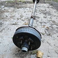 View of one end of the trailer axle showing the brake drum with 5 bolt lug pattern and bare axle shaft.
