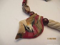 Close-up of multicolored sculpted polymer clay pendant with polished stone and round bead on necklace