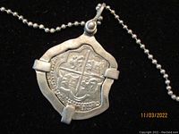 Close-up of front of Atocha replica coin pendant showing detailed design with Spain heraldic symbols.