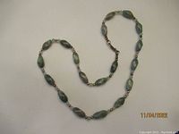 Full view of the green aventurine stone necklace laid flat, showing the alternating stones and beads.