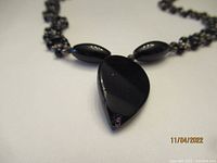 Close-up of the black onyx teardrop pendant and adjacent oval beads.