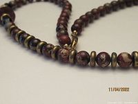 Close-up image showing round Blood Stone Jasper beads intermixed with brass disc spacers, highlighting the bead colors and finish.