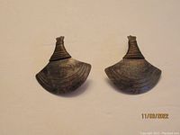 Front view of one pair of brass earrings showing fan-shaped design with linear engravings and wire wrapping at the top.