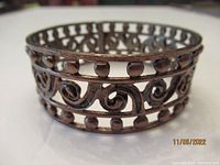 Front view of copper bracelet showing its circular cut-out design with swirls and circles.