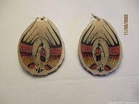 Front side of the pair of large earrings showing painted design on antler surface.