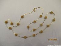 Gold tone necklace with coil spring ball beads lying flat on surface showing full length