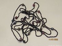 Full view of the long black glass bead necklace with larger accent beads laid out showing tangle of beads and length.