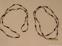 Two freshwater pearl necklaces laid side by side showing alternating pattern of black, white and gray pearls.