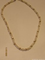Full view of the pearl and gold tone bead necklace showing the twisted strand design and clasp.