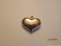 Close-up of sterling silver puff heart pendant, polished surface