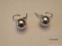 Front view of the pair of spherical, polished sterling silver drop earrings