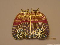 Front view of the 'Rainbow Cats' brooch showing red, purple, and blue enamel cat figures with gold-tone outlines.