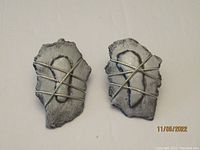 Front view of the pair of cat-shaped metal earrings showing the irregular shape and silver wire detail.