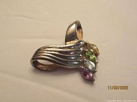 Silver pendant with multiple colored stones showing amethyst, blue topaz, citrine, and peridot stones set on a wavy patterned band.