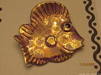 Porcelain fish brooch showing detailed design, texture, and colors with gold accents.