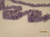 Close up of tumbled tanzanite stone chips showing purple hues and irregular shapes on the necklace.