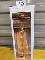 Box showing 10 inch glitter Christmas tree with LED lights. The box has product details and image of the tree lit up, with gold glitter finish and a small round base.
