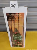 Box packaging for a 10 inch glitter Christmas tree with LED lights and battery operation shown with product information in multiple languages