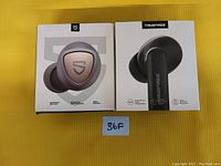 Front view of two boxes of wireless earbuds on yellow background, showing SoundPEATS and TrueFree packaging.