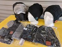 Three Bluetooth toques displayed on mannequin heads and laid flat, showing different styles including stretch knit, fleece lined floppy, and fuzzy water repellent with ear flaps and face mask.